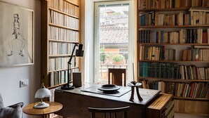 Un rincón acogedor para leer con un escritorio de madera, estanterías y vistas al exterior.
