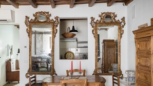 Un comedor con mesa de madera, sillas y espejos ornamentados con marcos dorados.