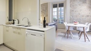 Eine moderne Küche mit Geschirrspüler, Spüle und Kaffeemaschine. Ein Essbereich mit Tisch und Stühlen ist ebenfalls vorhanden.
