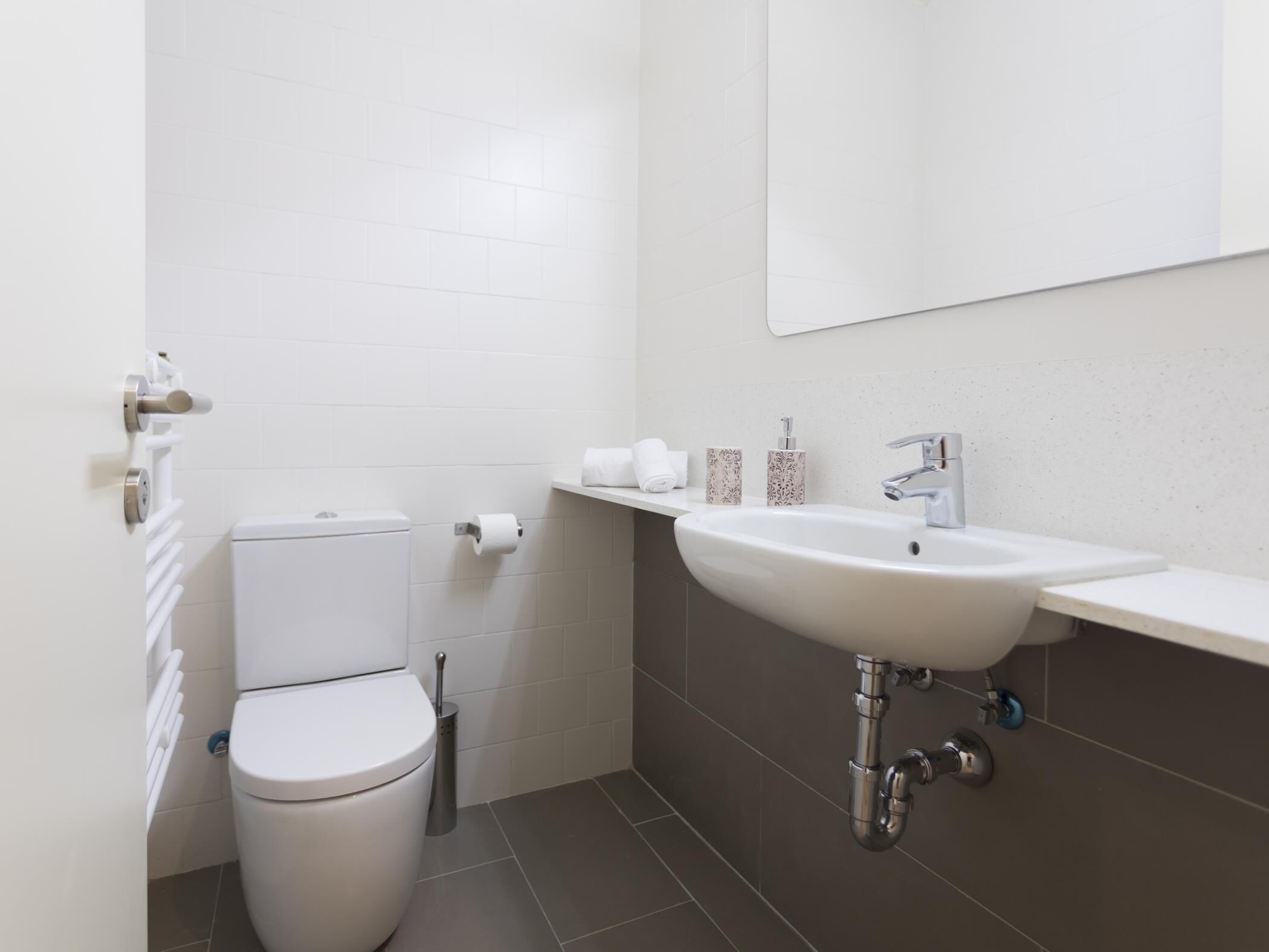 A modern bathroom with a toilet, sink, and mirror.