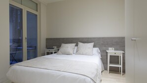 Ein modernes Schlafzimmer mit einem großen Bett, zwei Nachttischen und Blick durch eine Glastür.