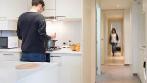 Moderni keittiö, jossa joku valmistaa ruokaa, on mikroaaltouuni ja hedelmäkulho työtasolla.