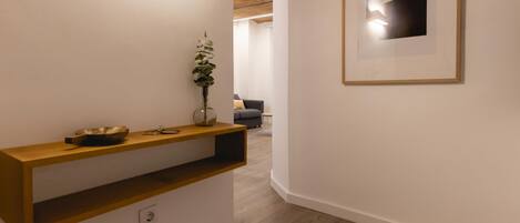 A hallway with a wooden console table, a vase with a plant, and a framed artwork on the wall.