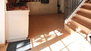 Una cocina con vigas de madera, una escalera y vista al área de estar.