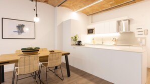 Una cocina moderna con armarios blancos, una mesa de comedor de madera y sillas de mimbre.