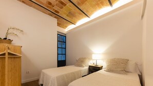 Una habitación pequeña y acogedora con dos camas individuales, un armario de madera y una ventana con vistas.