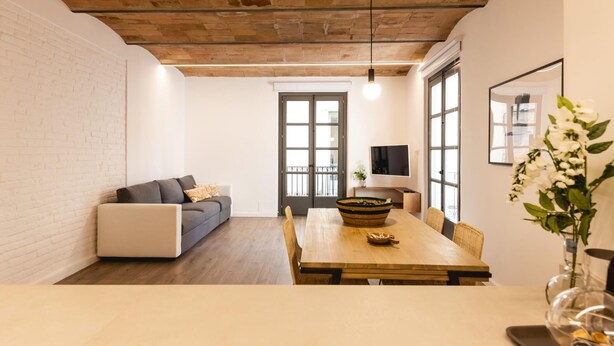 Una sala de estar moderna con sofá, mesa de comedor y un ventanal grande.