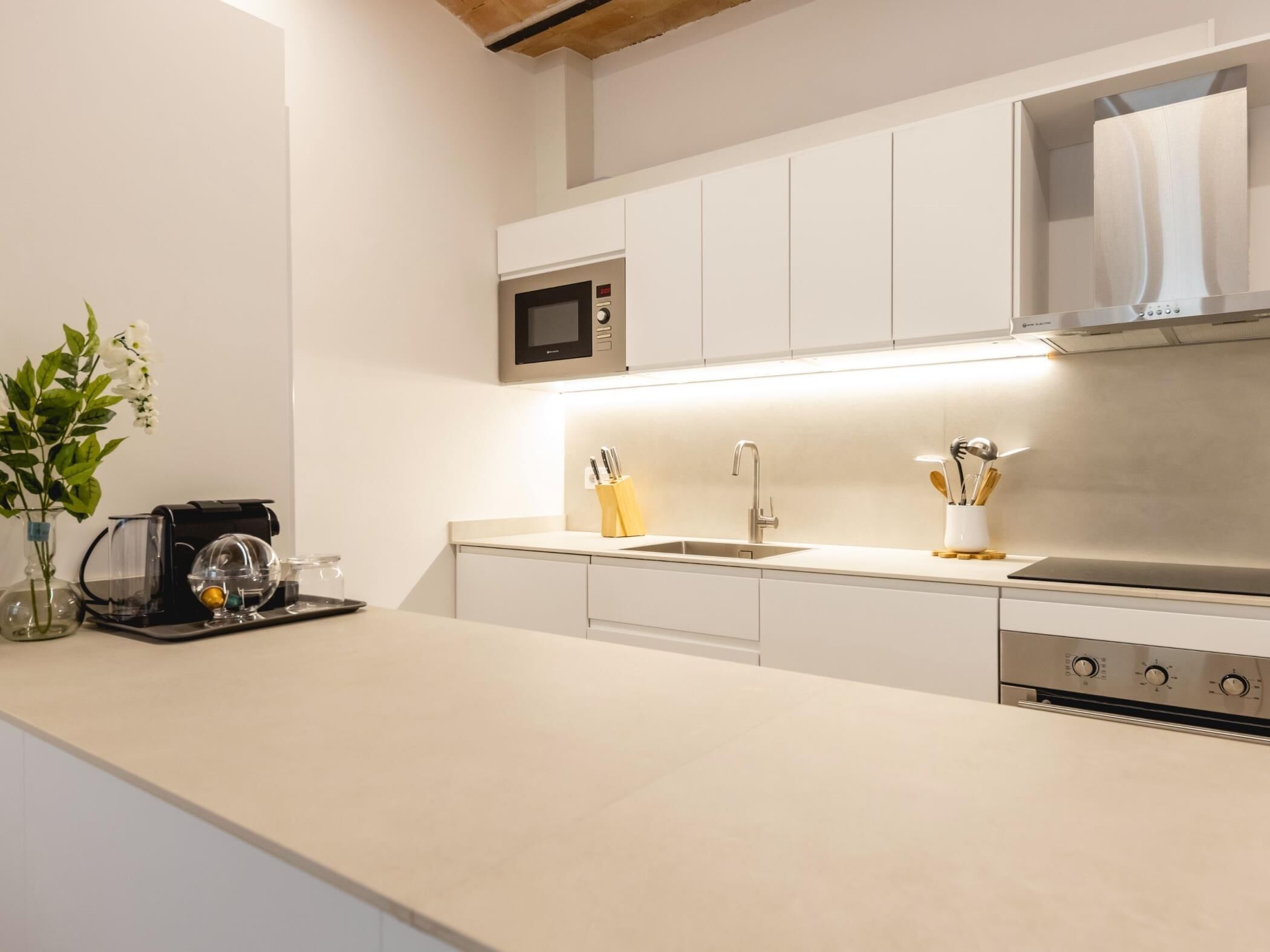 A modern kitchen with a built-in microwave, stainless steel sink, and a range hood.