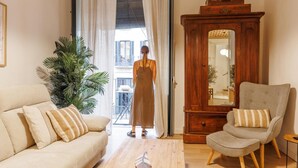 A living room with a sofa, armchair, wooden cabinet, and a potted plant. - Bravissimo Plaça del Vi, Authentic and Historic in the Barri Vell (Girona)