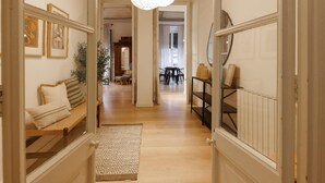 A hallway with a patterned ceiling, a wooden bench with cushions, a rug, and a dining area in the background. - Bravissimo Plaça del Vi, Authentic and Historic in the Barri Vell (Girona)