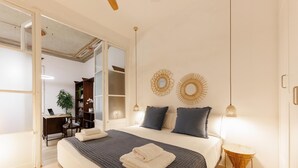 A bedroom with a large bed, a desk, and a chair in the corner. - Bravissimo Plaça del Vi, Authentic and Historic in the Barri Vell (Girona)