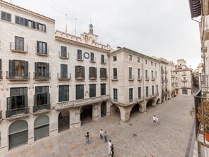 A spacious courtyard with multiple arches and a clock tower, surrounded by historic buildings with balconies and large windows. - Bravissimo Plaça del Vi, Authentic and Historic in the Barri Vell (Girona)