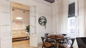 An open living area with a wooden dining table, chairs, a sofa, and a radiator. - Bravissimo Plaça del Vi, Authentic and Historic in the Barri Vell (Girona)