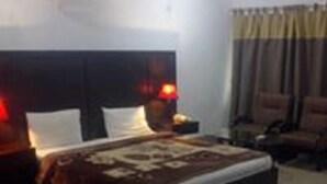 A hotel room with a bed, nightstands, and a chair. - Savvana Inn (Islamabad)