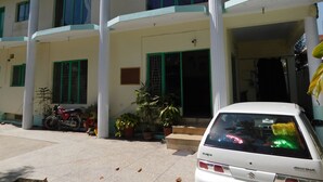 A building with multiple floors, large windows, and a white car parked in front. - Savvana Inn (Islamabad)
