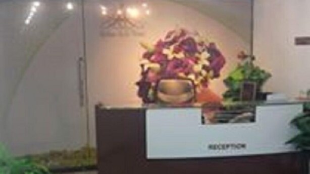A reception desk with a floral arrangement and a sign that reads "RECEPTION". - Savvana Inn (Islamabad)