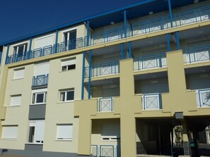 A multi-story building with balconies, windows, and a garage entrance.