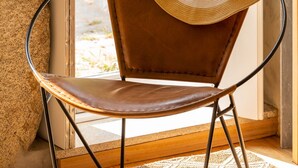 A chair with a straw hat placed on it, positioned next to a window with a view of greenery outside. - Garden of Camellias ★ Charming house near beach (4 bedrooms) (Porto)