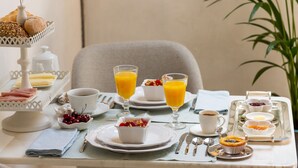 A breakfast setting with a variety of pastries, a fruit bowl, glasses of orange juice, and a coffee cup on a table. - Garden of Camellias ★ Charming house near beach (4 bedrooms) (Porto)