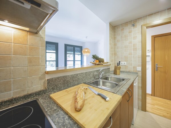 A modern kitchen with granite countertops, stainless steel sinks, and wooden cabinets. - Bravissimo Sant Pau, cozy 2-bedroom apartment in the centre (Girona)
