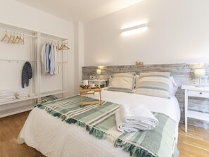A neatly arranged bedroom with a bed, bedside tables, a nightstand, a wardrobe, and a hanging rack with clothes. - Bravissimo Sant Pau, cozy 2-bedroom apartment in the centre (Girona)