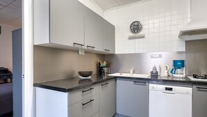 Una cocina moderna con armarios grises, encimera negra, lavavajillas y cafetera.