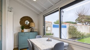 Un comedor con mesa y sillas, un armario azul, un espejo redondo y vistas al exterior.
