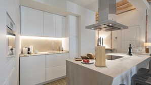A modern kitchen with white cabinetry, a central island, and a built-in stove. - Bravissimo Mercaders 3-1-2, unique and with 3 bedrooms in the historic center (Girona)