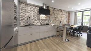 Eine moderne Küche mit Steinrückwand, integriertem Backofen und Essbereich mit Tisch und Stühlen.
