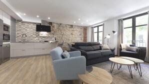 Ein modernes Wohnzimmer mit einer Küche, einem grauen Sofa, einem runden Couchtisch und einer Steinwand.
