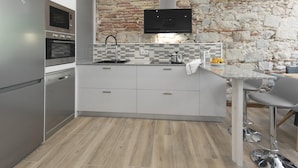 A modern kitchen with a stone wall backsplash, stainless steel appliances, and a flat-screen TV mounted above the counter. - Bravissimo Rambla Eiffel 2, 3 bedrooms, located next to the Eiffel Bridge (Girona)