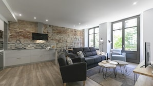 A modern living space with a kitchen, a grey sofa, a coffee table, and large windows. - Bravissimo Rambla Eiffel 2, 3 bedrooms, located next to the Eiffel Bridge (Girona)