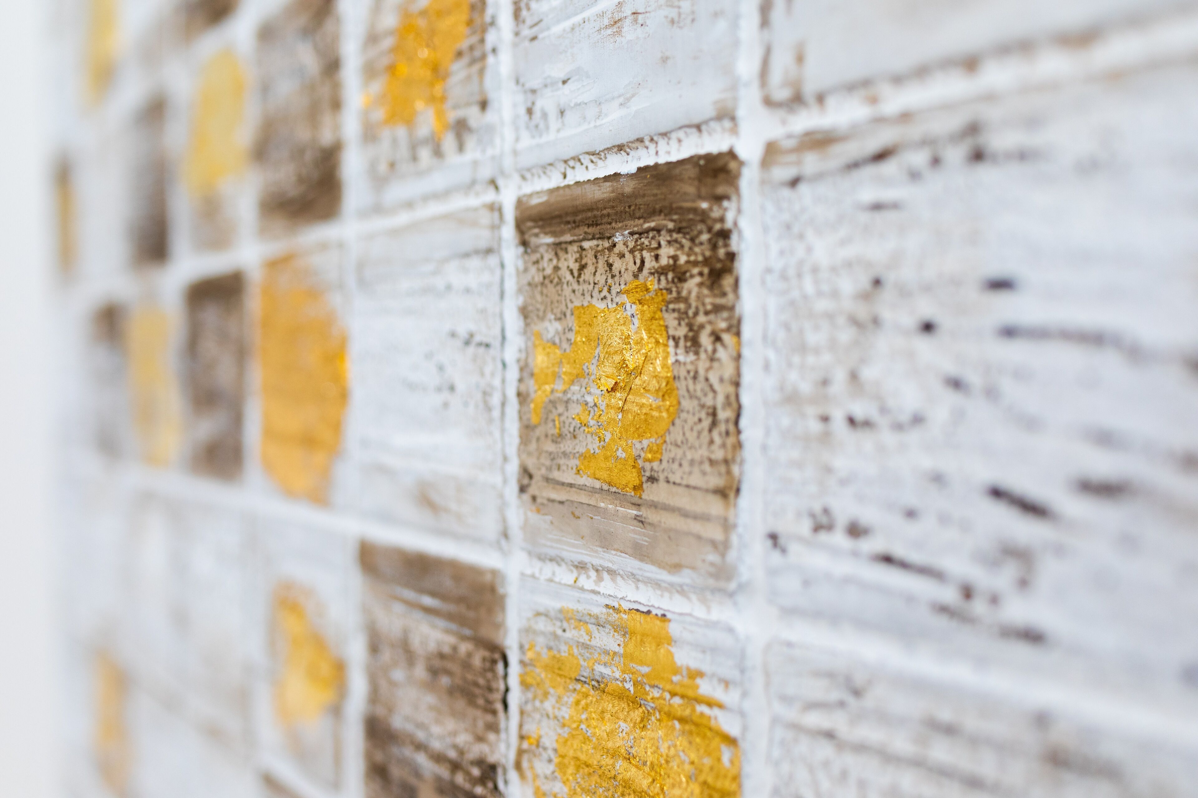 Primer plano de una pared con un diseño de baldosas cuadradas, algunas de ellas despegadas o dañadas.