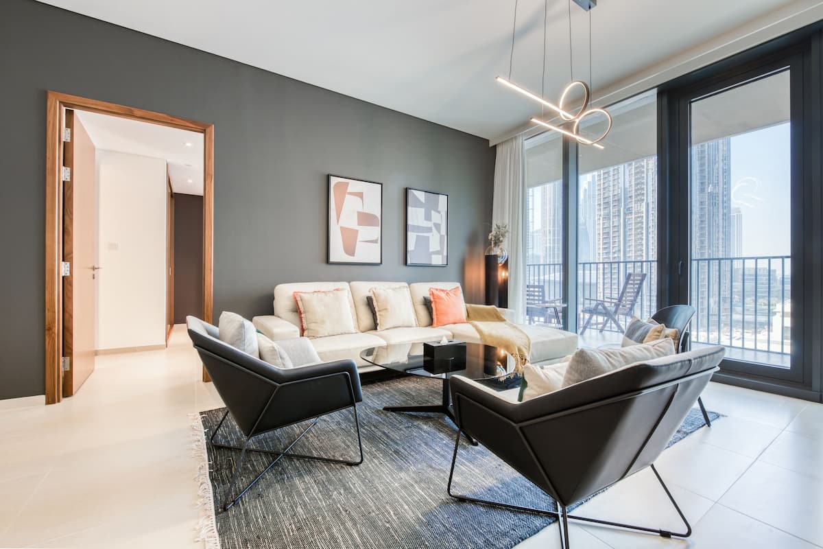 A modern living room with a sofa, two armchairs, a coffee table, and abstract wall art.