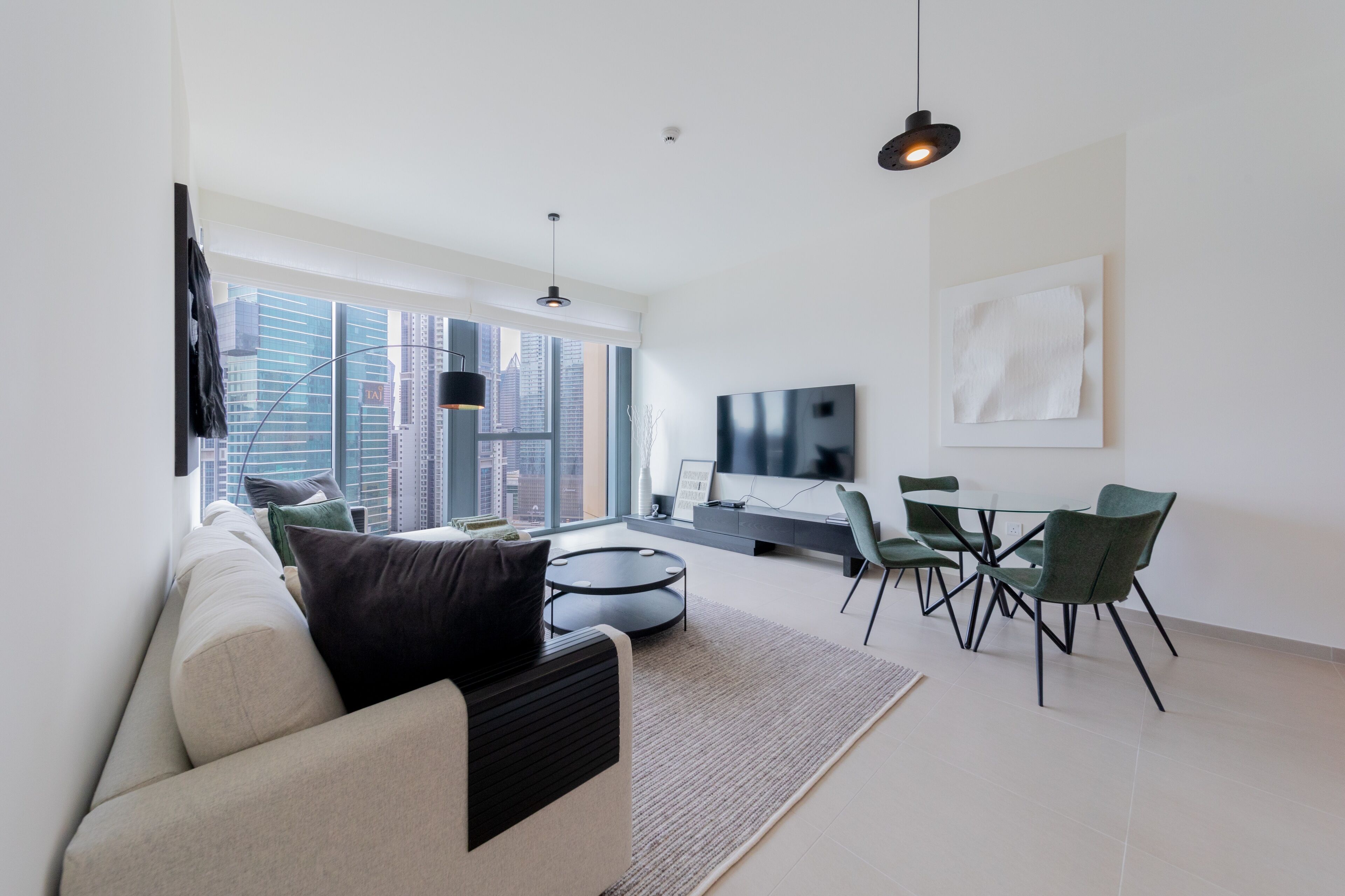 Een moderne woonkamer met een bank, een salontafel, een eethoek met stoelen, een televisie en een groot raam met uitzicht op de stad.