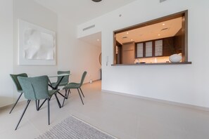 A modern kitchen with a built-in oven and a window above the counter. There is a dining area with a table and chairs. - EDEN'S Homes & Villas - BLVD Heights (Dubai)