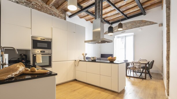 A modern kitchen with white cabinetry, stainless steel appliances, a wooden island, and a dining area with a table and chairs. - Bravissimo Bali, beautiful 2-bedroom apartment (Girona)
