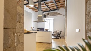 A modern kitchen with white cabinets, a wooden ceiling, and a central island. - Bravissimo Bali, beautiful 2-bedroom apartment (Girona)
