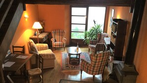 Una sala de estar acogedora con chimenea, una mesa de comedor y varias sillas a cuadros.