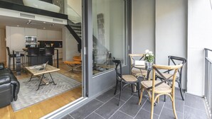 Un intérieur moderne comprenant un coin repas, une cuisine et un mur de verre donnant sur un balcon.