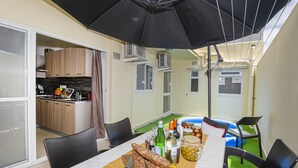 Ein Essbereich mit einem Tisch für zwei Personen, eine Küche im Hintergrund und eine Klimaanlage an der Wand.