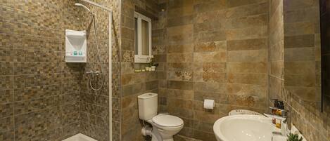 A bathroom with a shower, toilet, and sink, featuring mosaic tile walls and a modern design.
