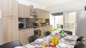Eine moderne Küche mit Holzausstattung, einer Mikrowelle und einer Essecke, die für das Frühstück gedeckt ist, mit Tellern, Tassen und einer Saftflasche.