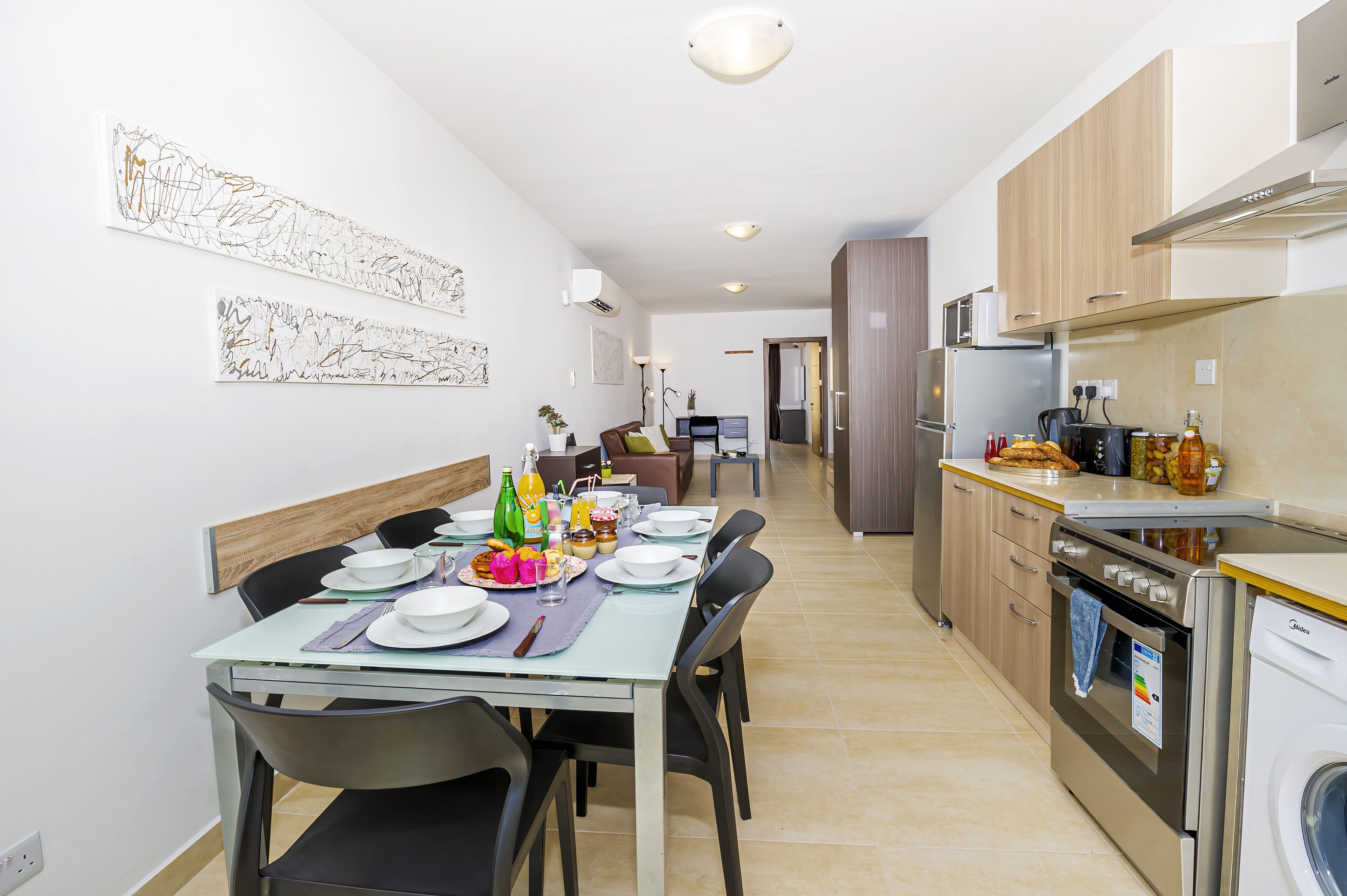 A modern kitchen with a dining area, equipped with a refrigerator, stove, and microwave.