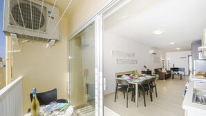 Een modern appartement met een eethoek, keuken en een balkon met airconditioning.