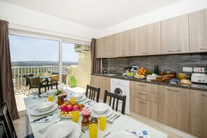 Een moderne keuken met houten kastjes, een inbouwoven en een eethoek met een ontbijt gedekte tafel.