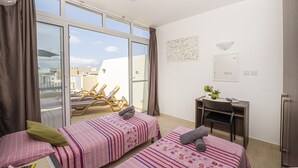 A room with two beds, a desk, and a view of the city. - Summer Breeze Penthouse with large Terrace and Hot Tub by Getaways Malta (Mellieha)