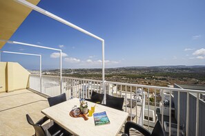A balcony with a table, chairs, and a book titled 'Sustaina'.