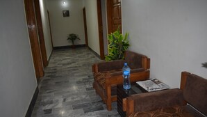Um corredor com porta de madeira, planta em vaso e área de estar com mesa e cadeiras.