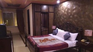 Quarto com cama de madeira, mesa de cabeceira com abajur e janela com cortinas.